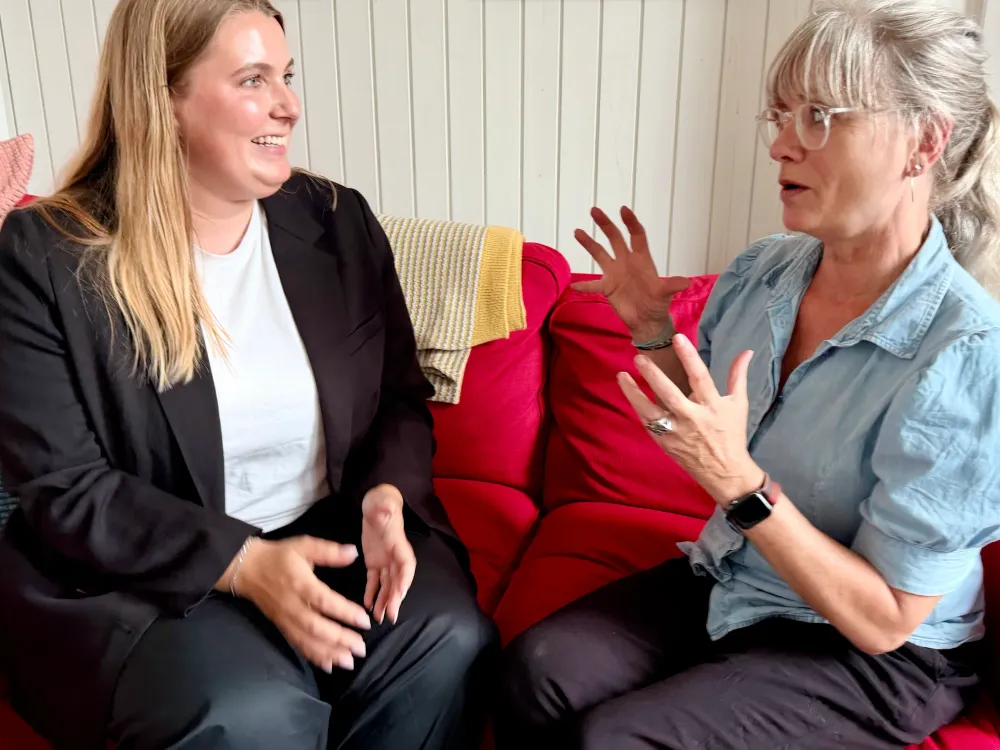 Lærerne Victoria Rosenbjerg og Lene Ishøy sidder i en rød sofa midt i en samtale.